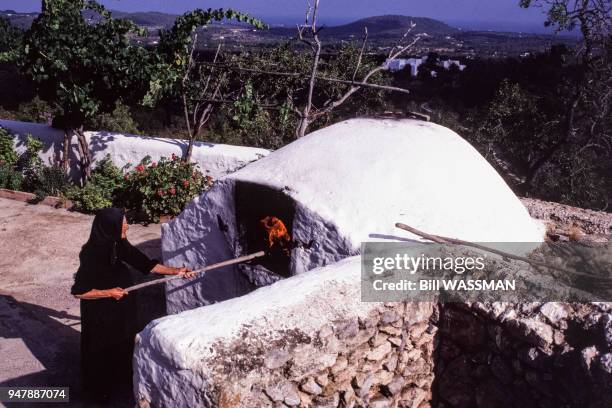 Femme âgée utilisant un four à pain à Ibiza, en octobre 1987, dans les îles Baléares, Espagne.