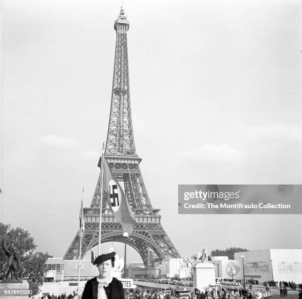 Woman at the 1937 Paris World Exhibition, with a large Nazi swastika flag flying in front of the Eiffel Tower, Paris, France 1937.