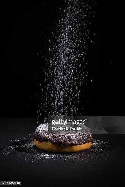 sprinkling sugar powder on delicious donut topped with chocolate - poedersuiker stockfoto's en -beelden
