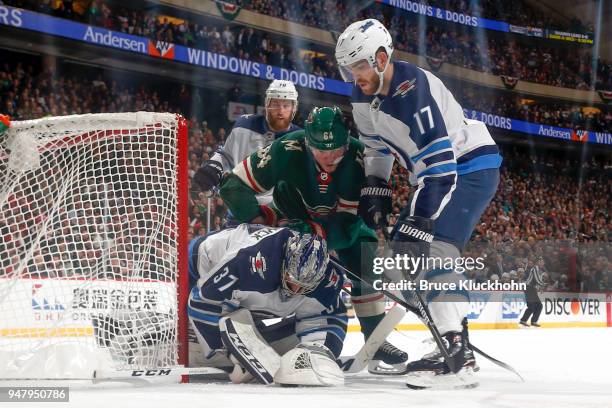 Connor Hellebuyck covers the puck while his teammates Adam Lowry and Joe Morrow of the Winnipeg Jets defend against Mikael Granlund of the Minnesota...