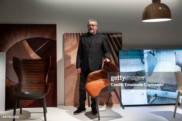 French designer Philippe Starck poses with one of his creations at the Kartell display stand during the Salone Internazionale del Mobile at Fiera di...