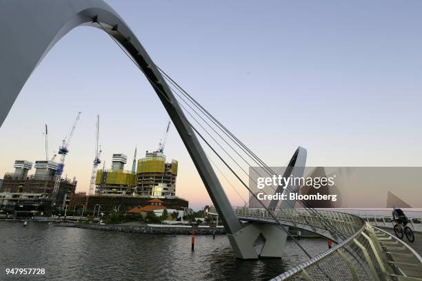 Cyclist rides across the Horseshoe Bridge towards developments under construction in the Elizabeth Quay area of Perth, Australia, on Wednesday, April...