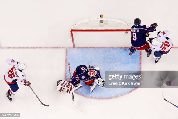 Lars Eller of the Washington Capitals slides the puck past Sergei Bobrovsky of the Columbus Blue Jackets and Zach Werenski of the Columbus Blue...