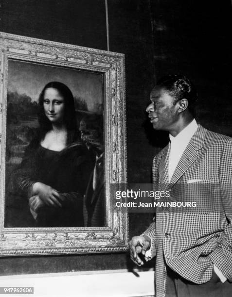 American singer Nat King Cole at Louvre Museum looking at famous painting La Joconde in 1956 in Paris, France.