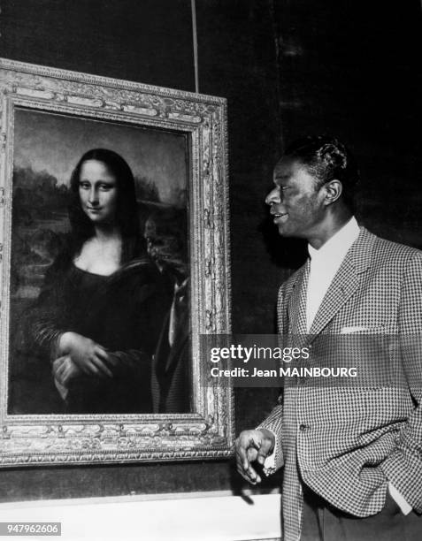 American singer Nat King Cole at Louvre Museum looking at famous painting La Joconde in 1956 in Paris, France.