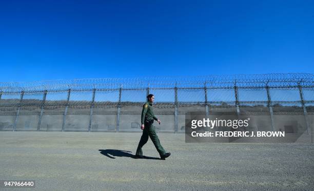 Customs and Border Protection agent Tekae Michael walks inside the Border Infrastructure System which separates the US from Mexico with a fence and...