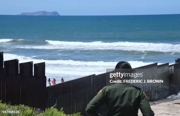 Customs and Border Protection agent watches from near the end of the border structure which runs into the Pacific Ocean in San Diego, California as...