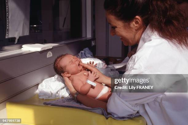 Sage-femme donnant les soins à un nouveau-né dans une maternité en France, circa 1990.