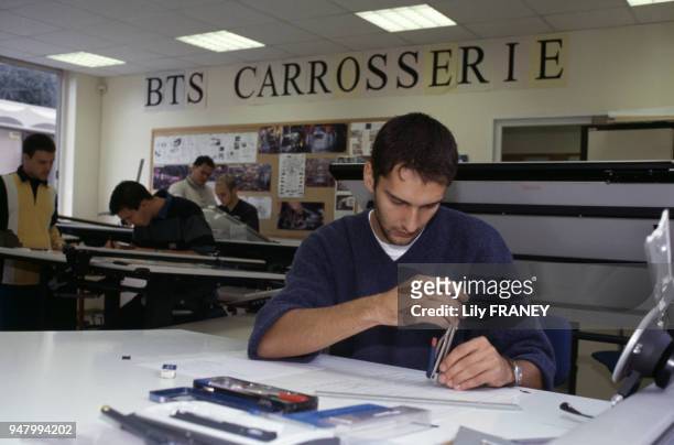Apprenti en BTS carrosserie dessinant des plans, en France, en septembre 1999.