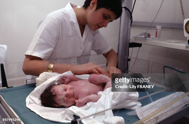 Sage-femme donnant les premiers soins à un nouveau-né dans une maternité en France, circa 1990.