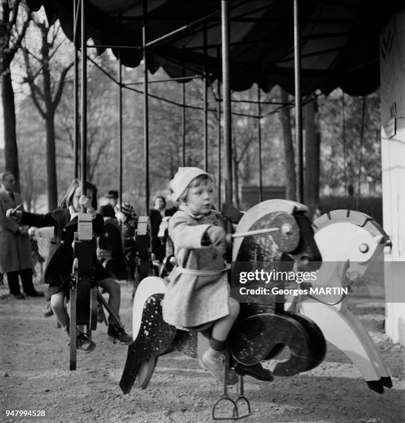 Christine monte sur un cheval de bois dans un manege, circa 1960 en France.