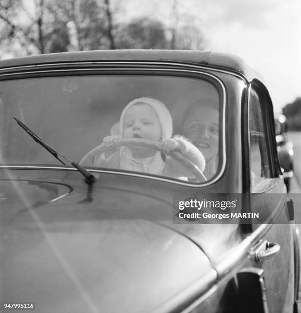 Une mere et son enfant jouant dans une voiture, circa 1950 en France.