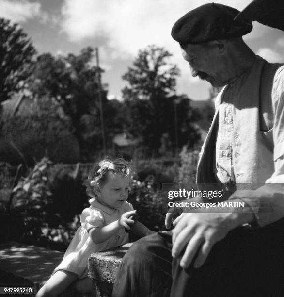 Un homme jouant avec une petite fille dans un jardin, circa 1960 en France.