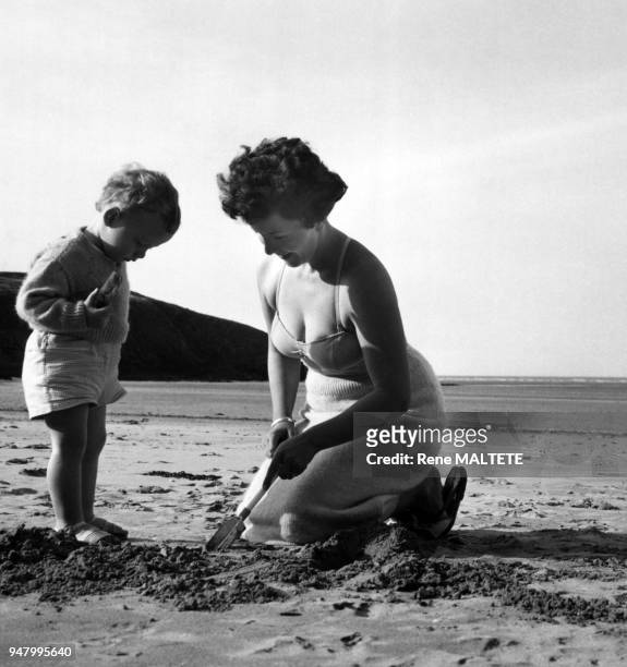 Femme jouant avec son enfant sur la plage, en 1961, France.