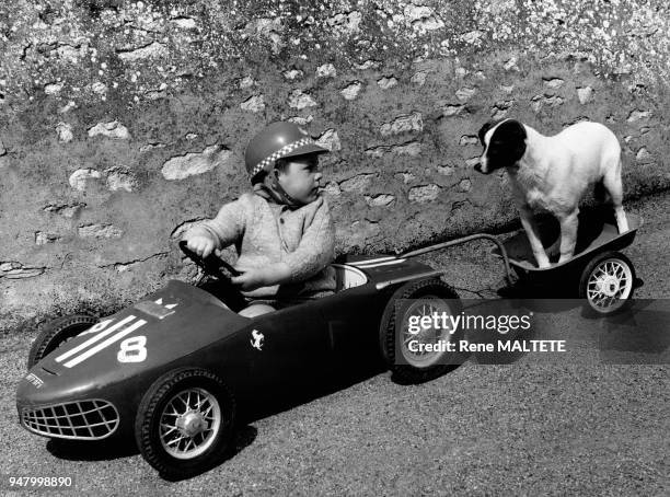 Enfant tirant son chien avec une voiture à pédales, dans le Loiret, en 1967, France.