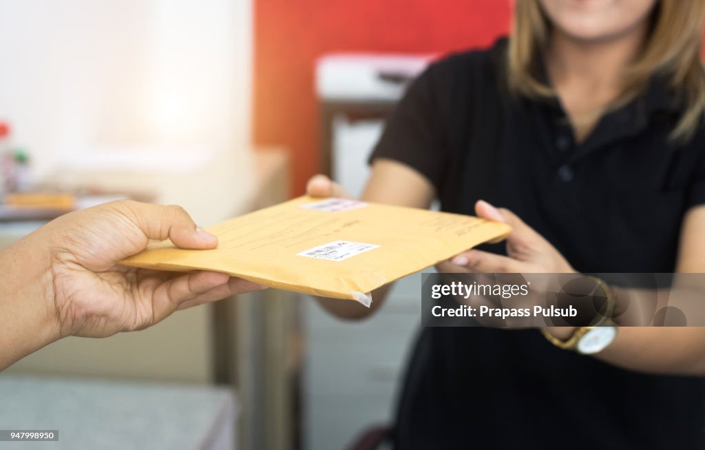Male hand send mail envelope to the female of post office before sending