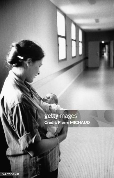 Jeune maman avec son bébé dans une maternité, en 1988, France.