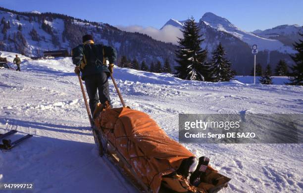 Secouriste de montagne évacuant un blessé sur une civière, sur une piste de ski, en mai 1997, en Haute-Savoie, France.