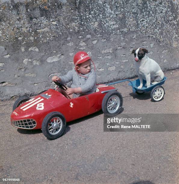 Enfant tirant son chien avec une voiture à pédales, dans le Loiret, en 1967, France.