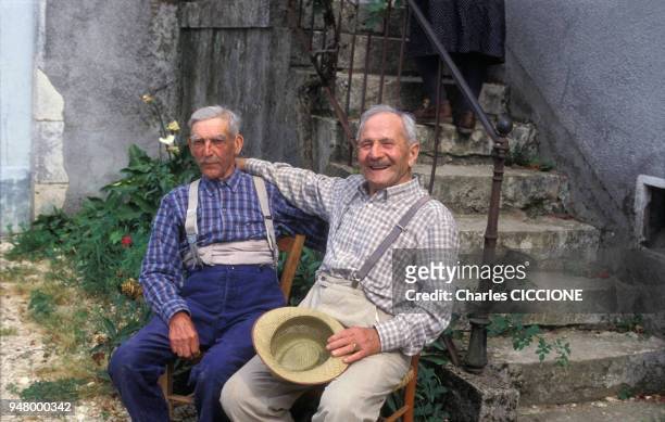 Hommes âgés posant dans une cour, en juillet 1984, en France.