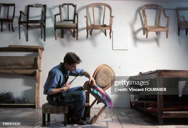 Menuisier réparant une chaise dans son atelier en France, en février 1981.