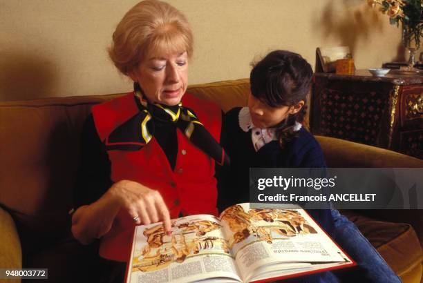 Petite fille lisant un livre avec sa grand-mère, en décembre 1990, France.