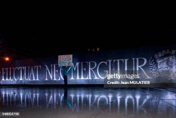 Le 'poète activiste', Voltuan, portant une pancarte 'Devoir de mémoire' devant la banderole avec l'inscription 'Fluctuat nec mergitur' signifiant 'Il...