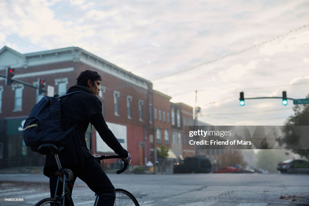 Early morning commuter waits on bicycle at stoplight in small town