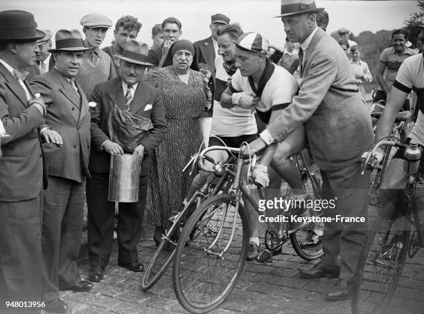 Un cycliste au ravitaillement pendant la course organisée par la revue 'Comoedia' pour les rédacteurs et journalistes sportifs, en France en 1934.