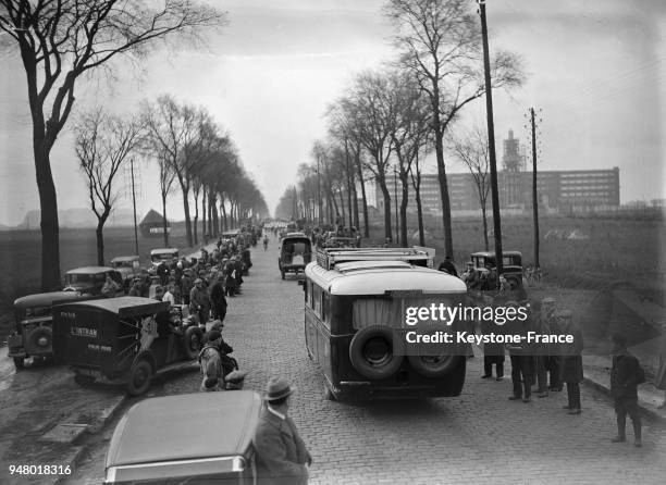 Les spectateurs en voiture et car attendent le passage des cyclistes, en France en mars 1934.