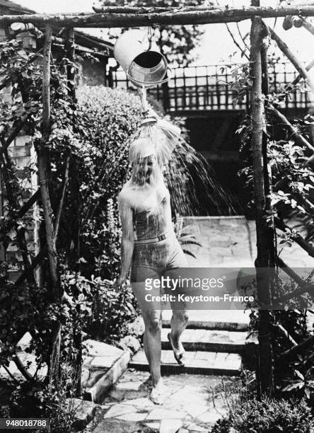 Jeune femme se rafraîchissant grâce à une drôle de douche confectionnée avec un arrosoir, en France en 1933.