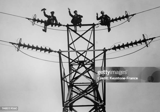 Trois électriciens au travail au sommet d'un pylône électrique, en France en 1934.