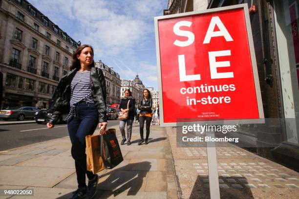 Shoppers carry bags as they pass a sale sign for outside a The GAP Inc. Retail store on Regent Street in London, U.K., on Tuesday, April 17, 2018....