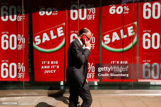 Man passes sale signs in the window of a New Look Retail Group Ltd. Clothing retail store, owned by Brait SE, store in Oxford Street in central...