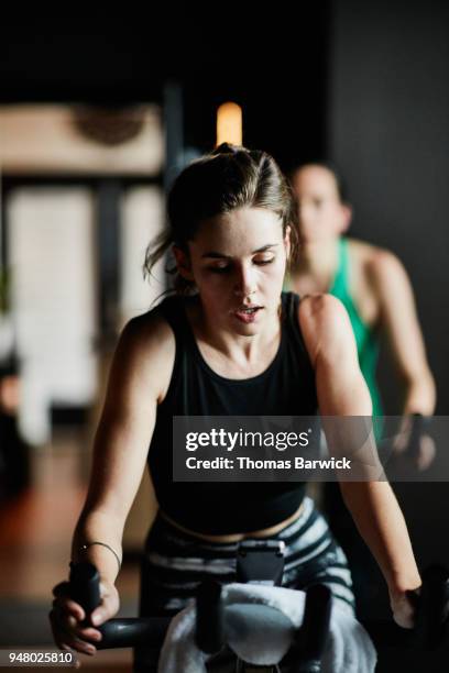woman breathing heavily while riding stationary bike in cycling studio - cyclette foto e immagini stock