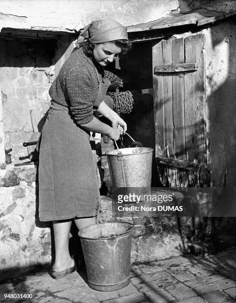 Farm woman drawing water from her well, circa 1930. Agricultrice puisant de l'eau dans son puits, vers 1930.