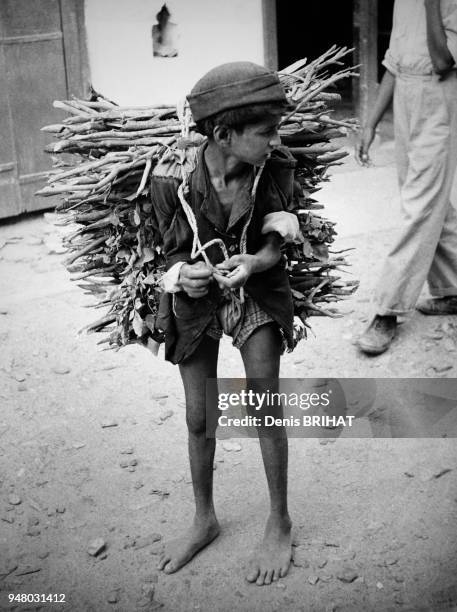 Enfant transportant un fagot de bois sur le dos, en avril 1965.
