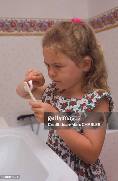 Petite fille mettant du dentifrice sur sa brosse à dents, circa 1990.