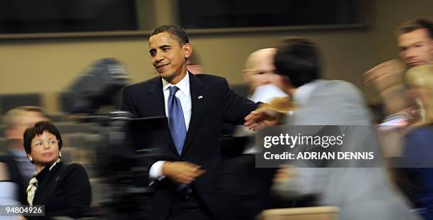 Onlookers stretch to shake the hand of US President Barack Obama as he walks through the press conference room at the Bella Center in Copenhagen on...