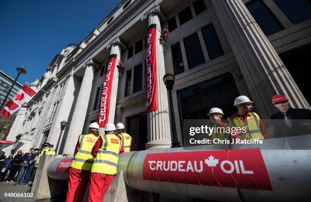 Greenpeace activists unfurl banners after building a wood and card 'oil pipeline' outside the Canadian High Commission, Canada House, to protest...