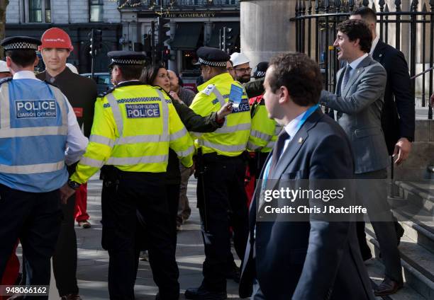 Canadian Prime Minister Justin Trudeau leaves Canada house past a cardboard cut out of himself whilst Greenpeace activists build a wood and card 'oil...