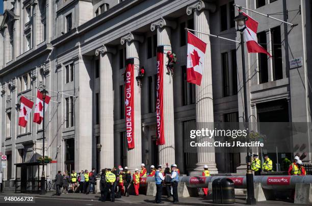 Greenpeace activists unfurl banners after building a wood and card 'oil pipeline' outside the Canadian High Commission, Canada House, to protest...