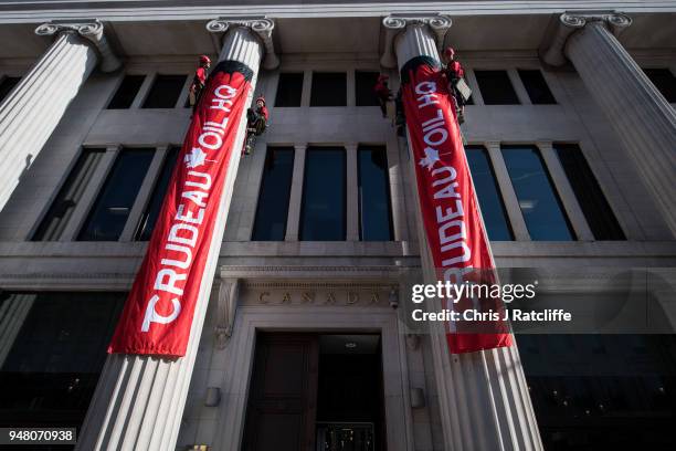 Greenpeace activists unfurl banners after building a wood and card 'oil pipeline' outside the Canadian High Commission, Canada House, to protest...