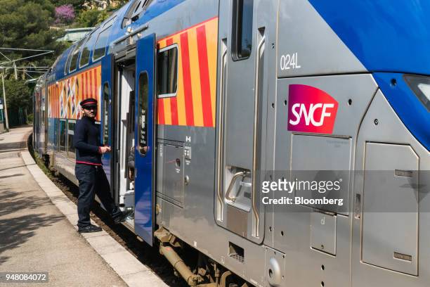 An employee of French national railway operator Societe Nationale des Chemins de Fer waits for passengers to board a Transport Express Regional train...