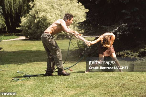 Jeune couple jouant avec un tuyaux d'arrosage.