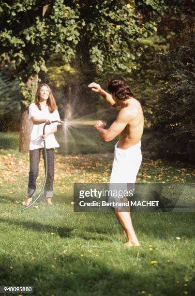 Jeune couple jouant avec un tuyaux d'arrosage.