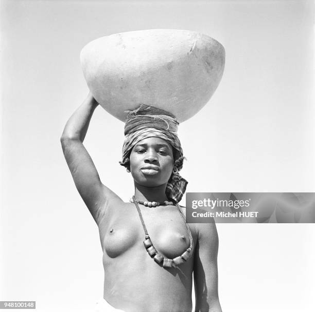 Une femme porte une calebasse au Mali vers 1950-1960.