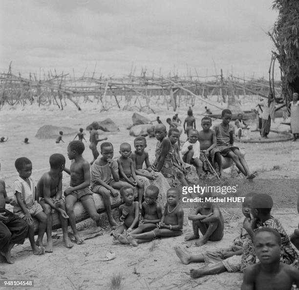 Groupe d'enfants Enya devant une pêcherie traditionnelle sur le fleuve Congo, dans la province Orientale, circa 1950, République démocratique du...
