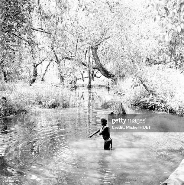 Une femme prend un bain dans une mare au Tchad vers 1950-1953.