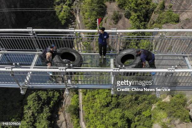 Participants push 200 Kg tyres on a 300-meter-long glass suspension bridge during a strongman competition at the Shiniuzhai National Geological Park...